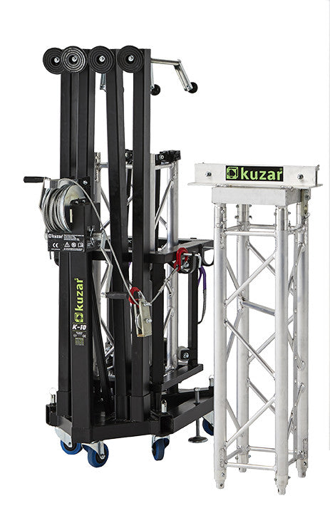 Compact folded view of the Kuzar K-10 tower lift base on swivel wheels next to a truss section, optimized for space-saving storage and European transport.
