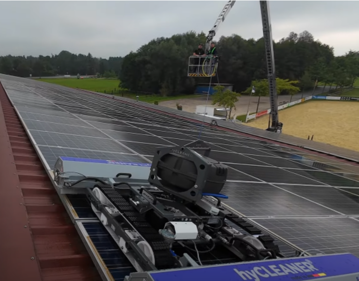 Robot per la pulizia del pannello solare su un tetto con un cielo nuvoloso e alberi sullo sfondo - imagen 11