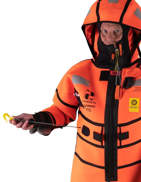 Hansen Protection SeaNordic Wet Suit 82606– A 6-hour immersion suit produced in extra strong flame-retardant neoprene. SeaNordic is equipped with an emergency light and has an integrated sprayhood that protects the face from waves and possibly seabirds. The hood has an innovative inflatable bladder for improved water tightness of the face seals, improved floatation and freeboard. The suit is certified for use without a lifejacket and is perfect as a survival suit on board fishing vessels, merchant ships and