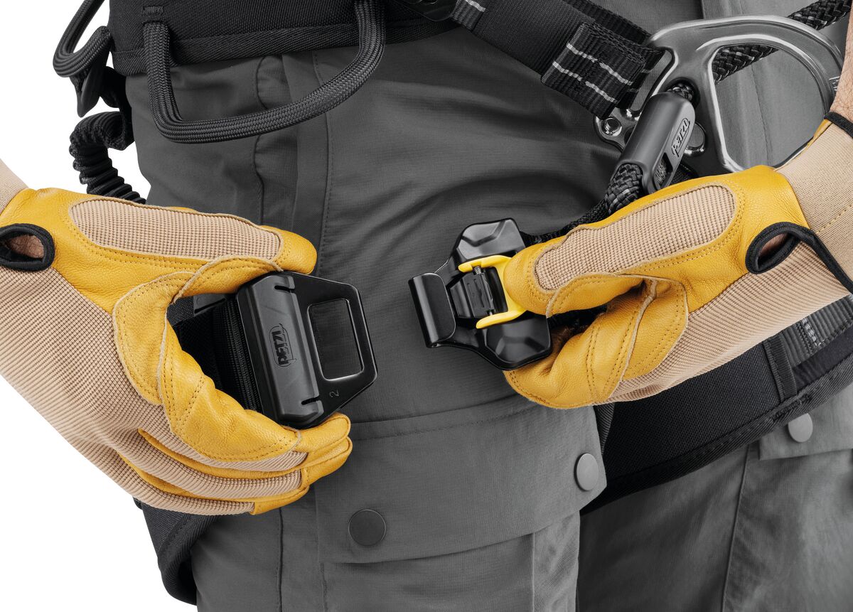 Close-up of hands wearing yellow gloves adjusting a black belt buckle on gray pants. - imagen 5