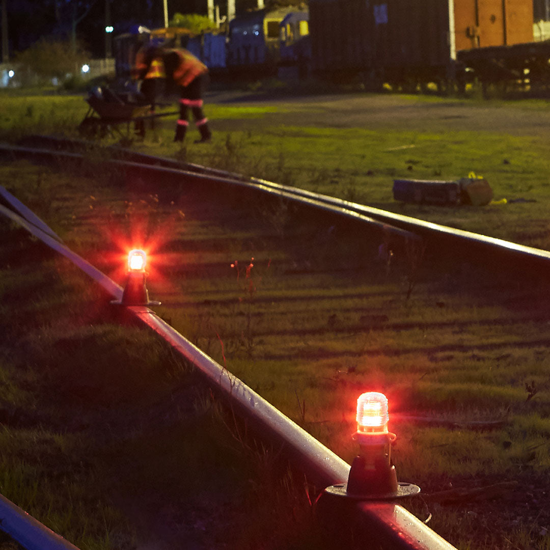 Red warning lights on a railway track with a person working in the background. - imagen 4