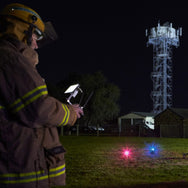 Person in firefighting gear operating a drone with a lit tower in the background - imagen 4