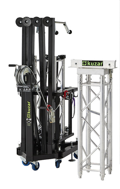 Compact folded view of the Kuzar K-10 tower lift base on swivel wheels next to a truss section, optimized for space-saving storage and European transport.