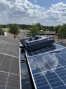 Solar panels on a roof with a clear sky and trees in the background