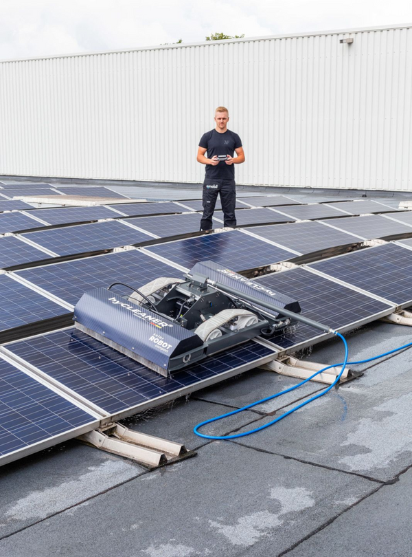 Person standing on a rooftop with solar panels and cleaning equipment.