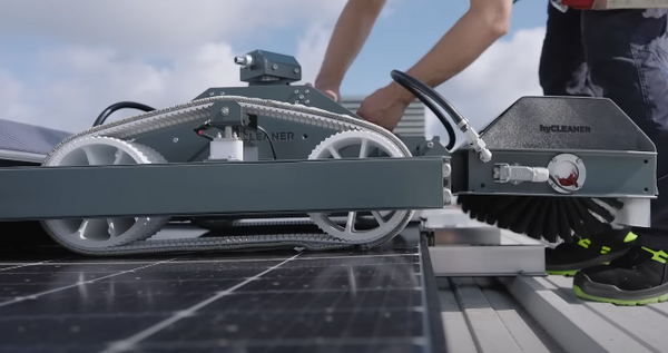 Person using a solar panel cleaning machine on a roof