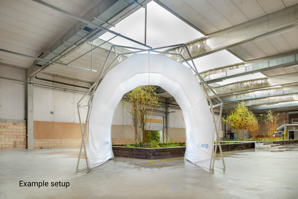 White inflatable tunnel structure inside a warehouse with plants outside